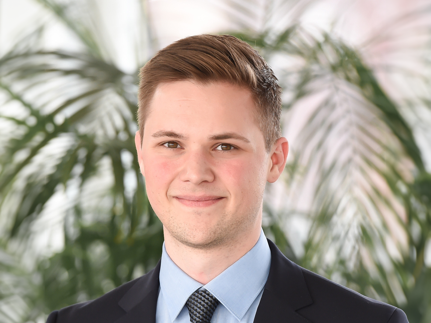 Eine Wissenschaftlerin und ein Wissenschaftler arbeiten hinter einer Glasfassade und mischen Chemikalien mit Großgeräten.