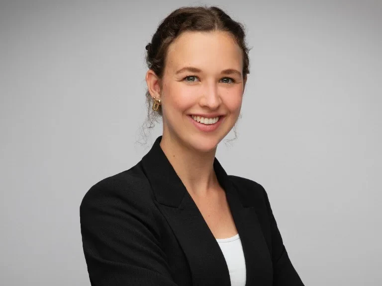 Eine Wissenschaftlerin und ein Wissenschaftler arbeiten hinter einer Glasfassade und mischen Chemikalien mit Großgeräten.